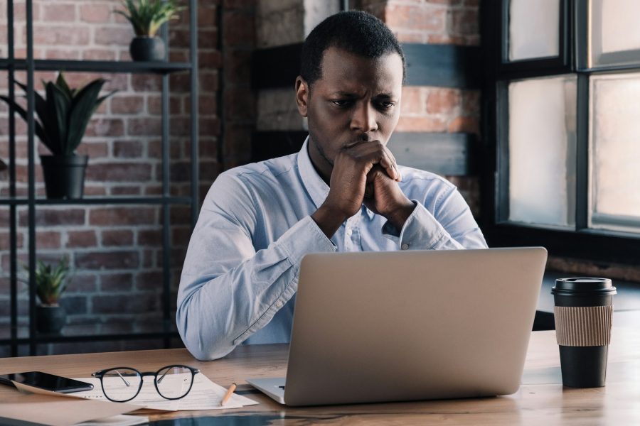 Casual african american man works on project at office thinking of financial risks